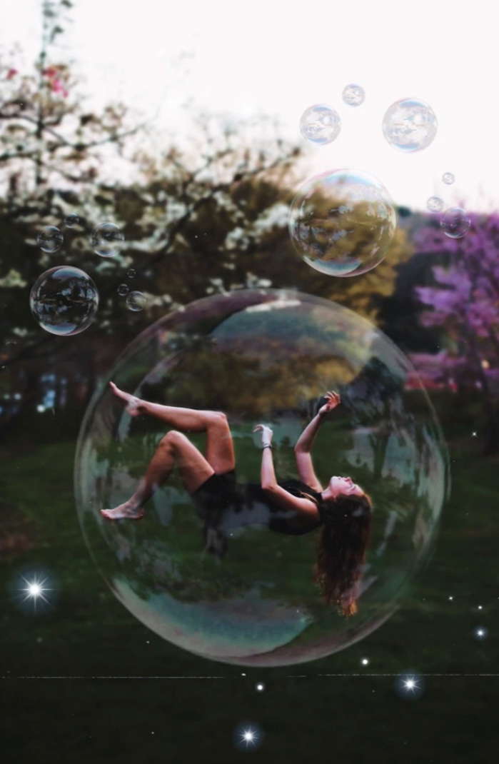 Woman floating in a big bubble with smaller bubbles floating around her