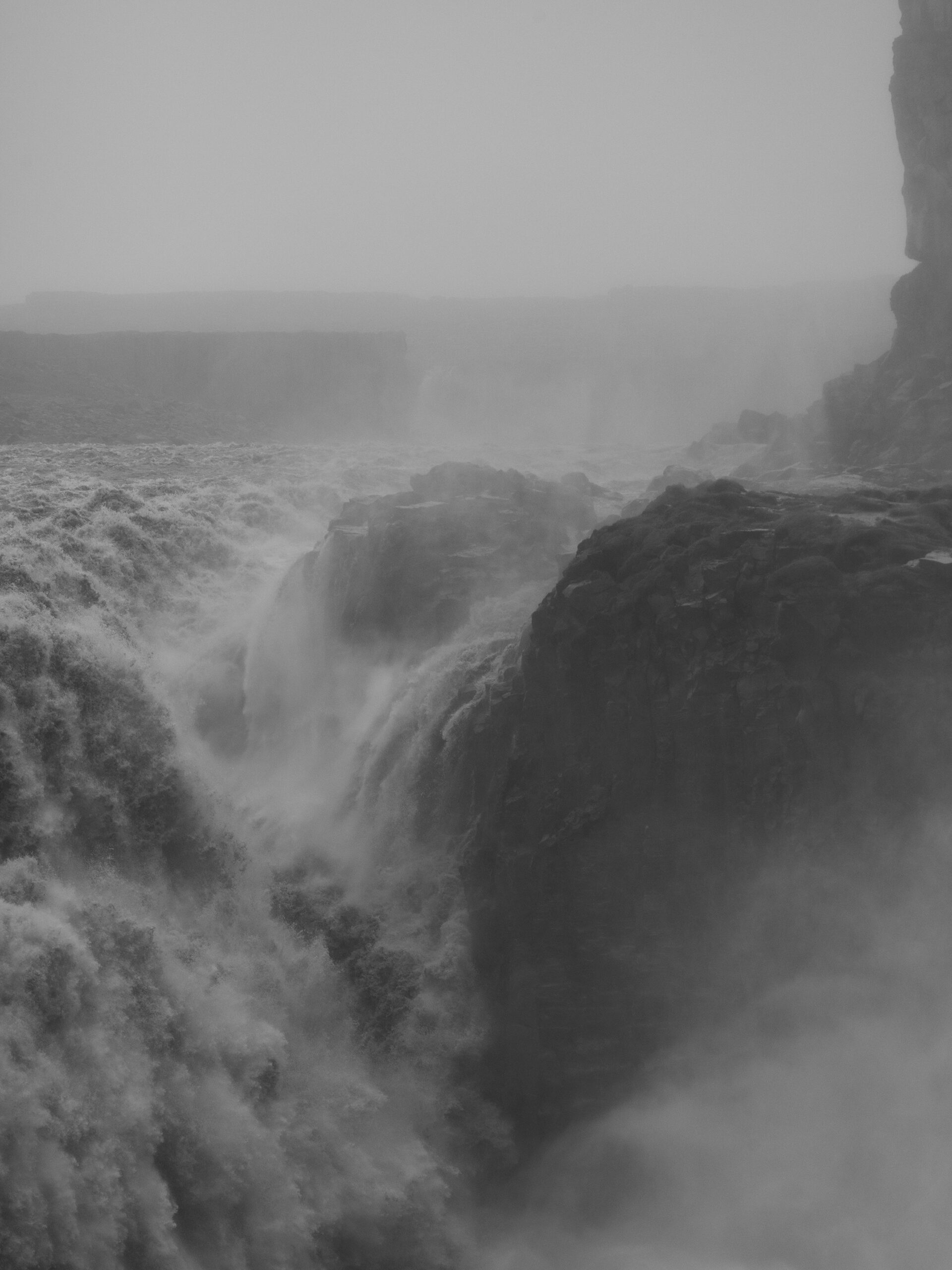 Massive water pouring violently over rock structures with mist clouding the air
