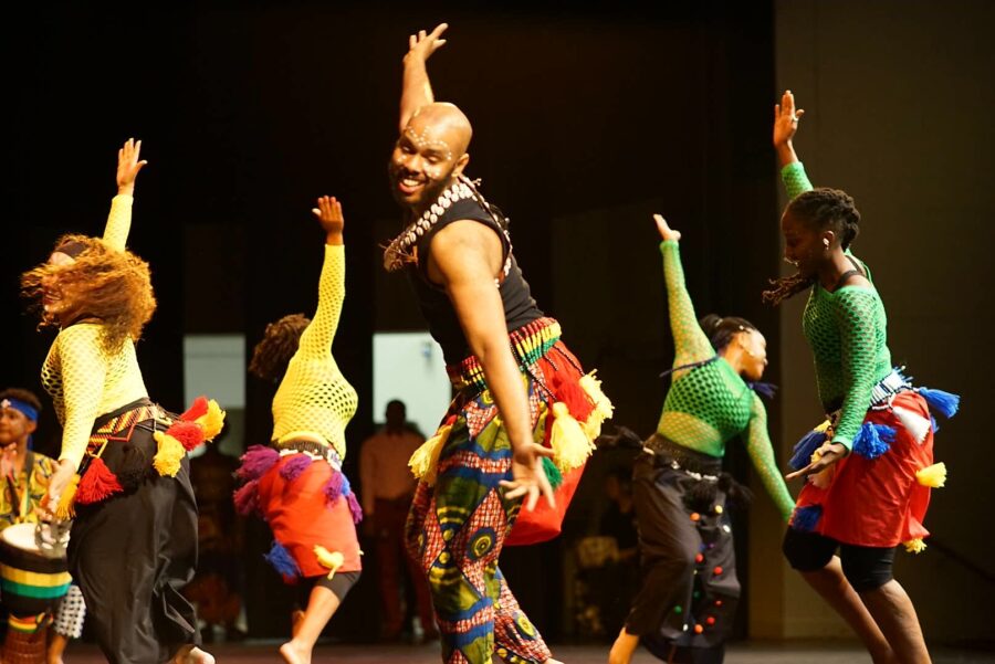 Dancers dressed in red, yellow, black and green outfits
