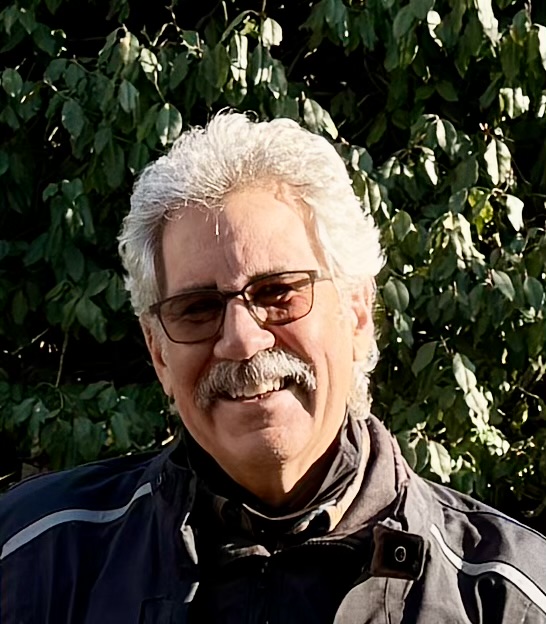 Architect, Seab A. Tuck smiles in front of a tree.