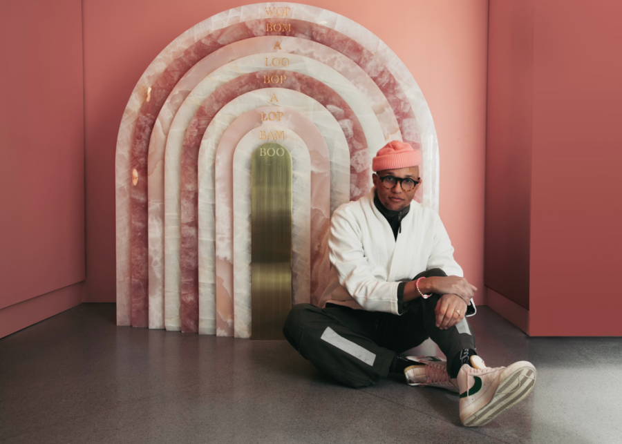 Shabazz Larkin sitting on the ground in front of a dome shaped pink-toned sculpture