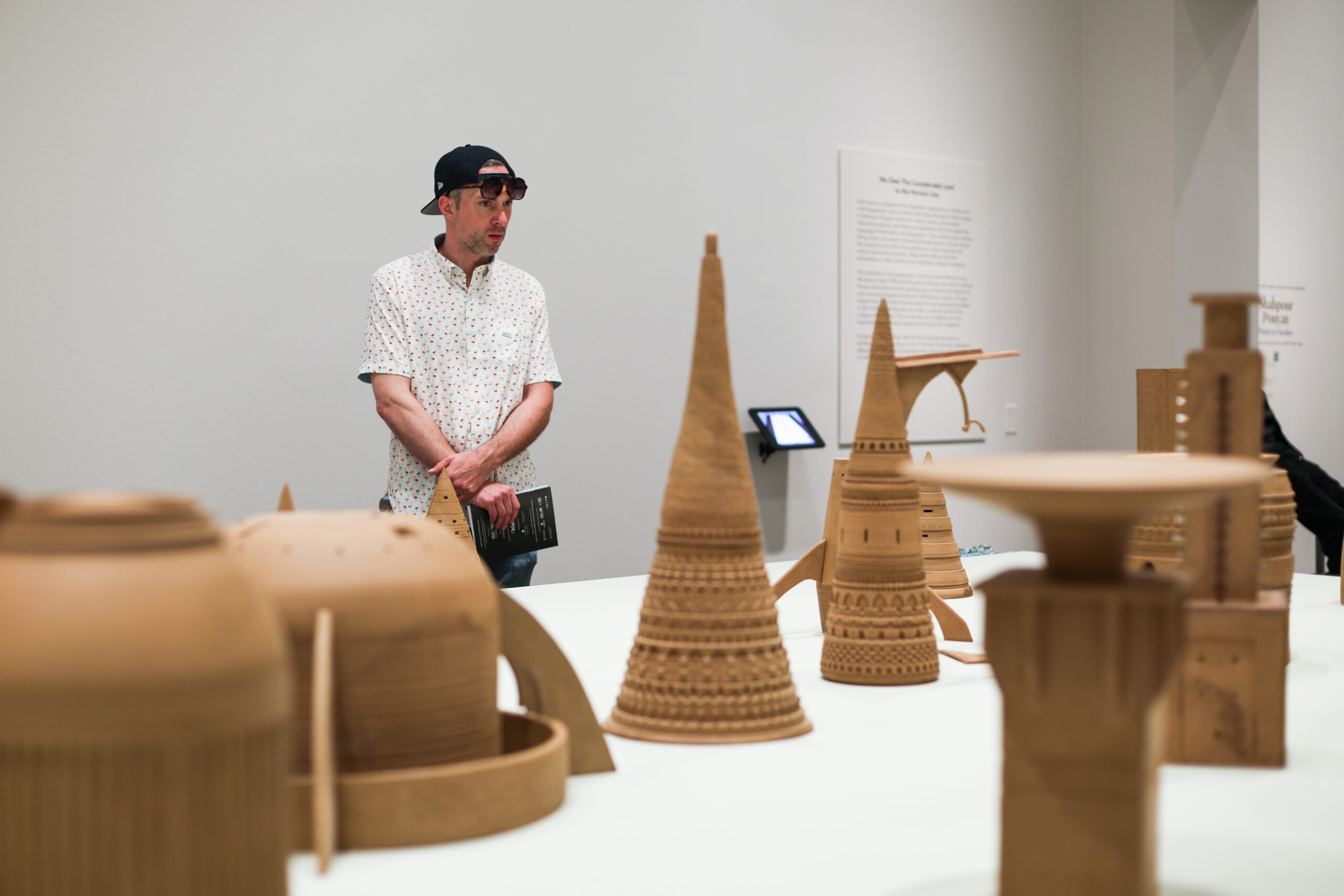 Man looking at several clay sculptures in varying shapes