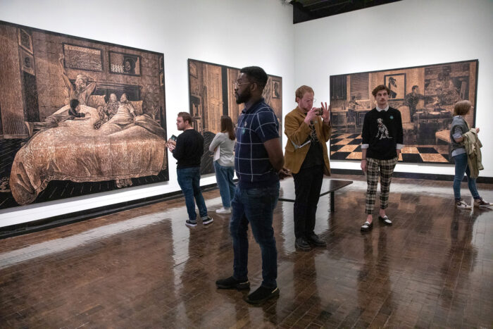 Several people looking at LaToya Hobb's artwork