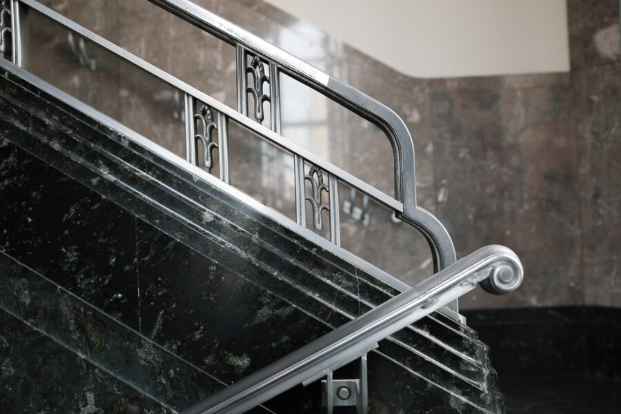 Close up view of metal art deco bannister along marble stairwell