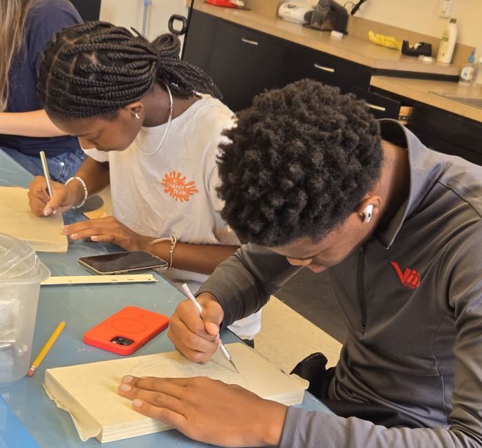 Two teens sitting at a table drawing