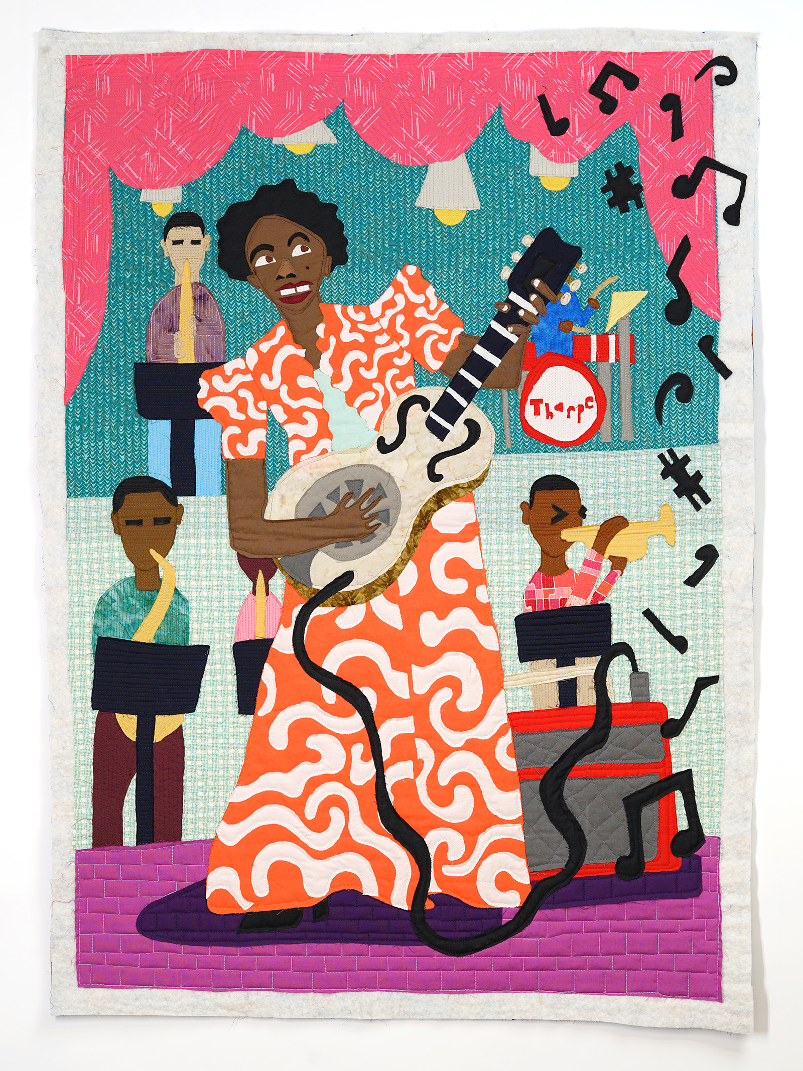 Black woman in a bright orange dress with white squiggly lines playing an electric guitar with children playing other instruments in the background