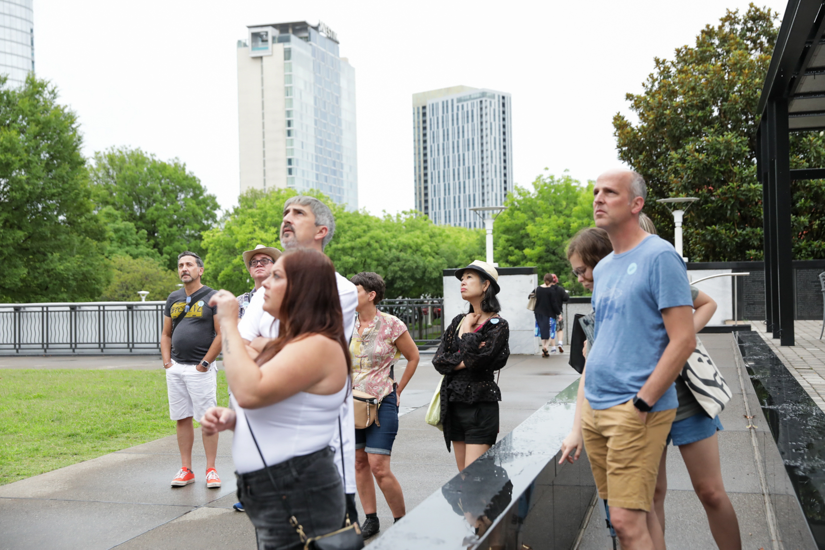 Group of people standing outside, looking at a building out of frame