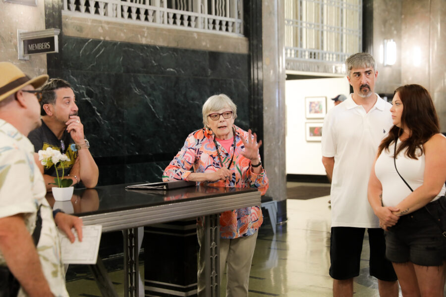 Woman leaning against table talking to tour group