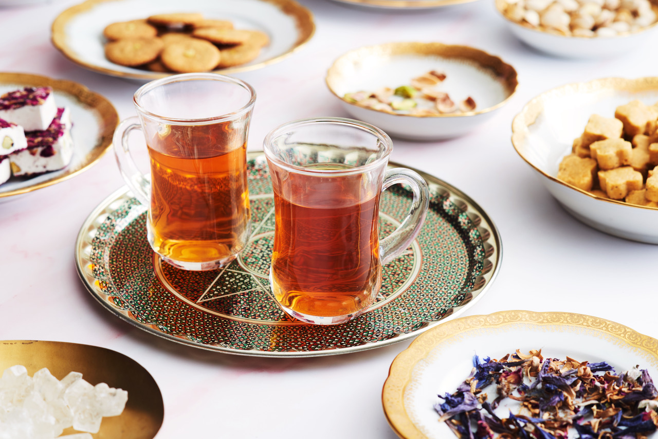 Two cups of tea sitting on a platter with light foods surrounding