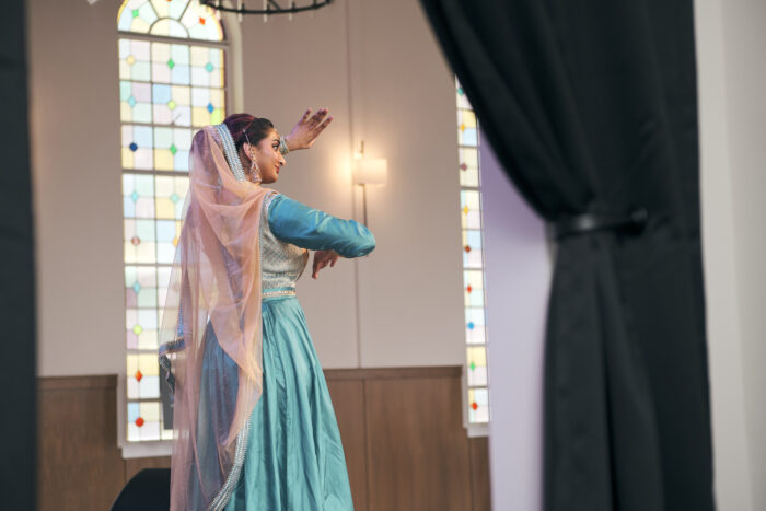 Woman dressed in a turquoise blue dress with a pink veil dancing