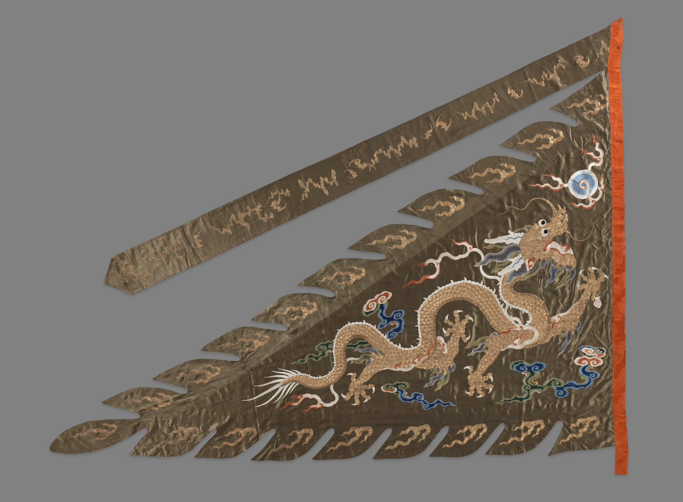 A tan-colored Asian style dragon on a triangular brown flag.