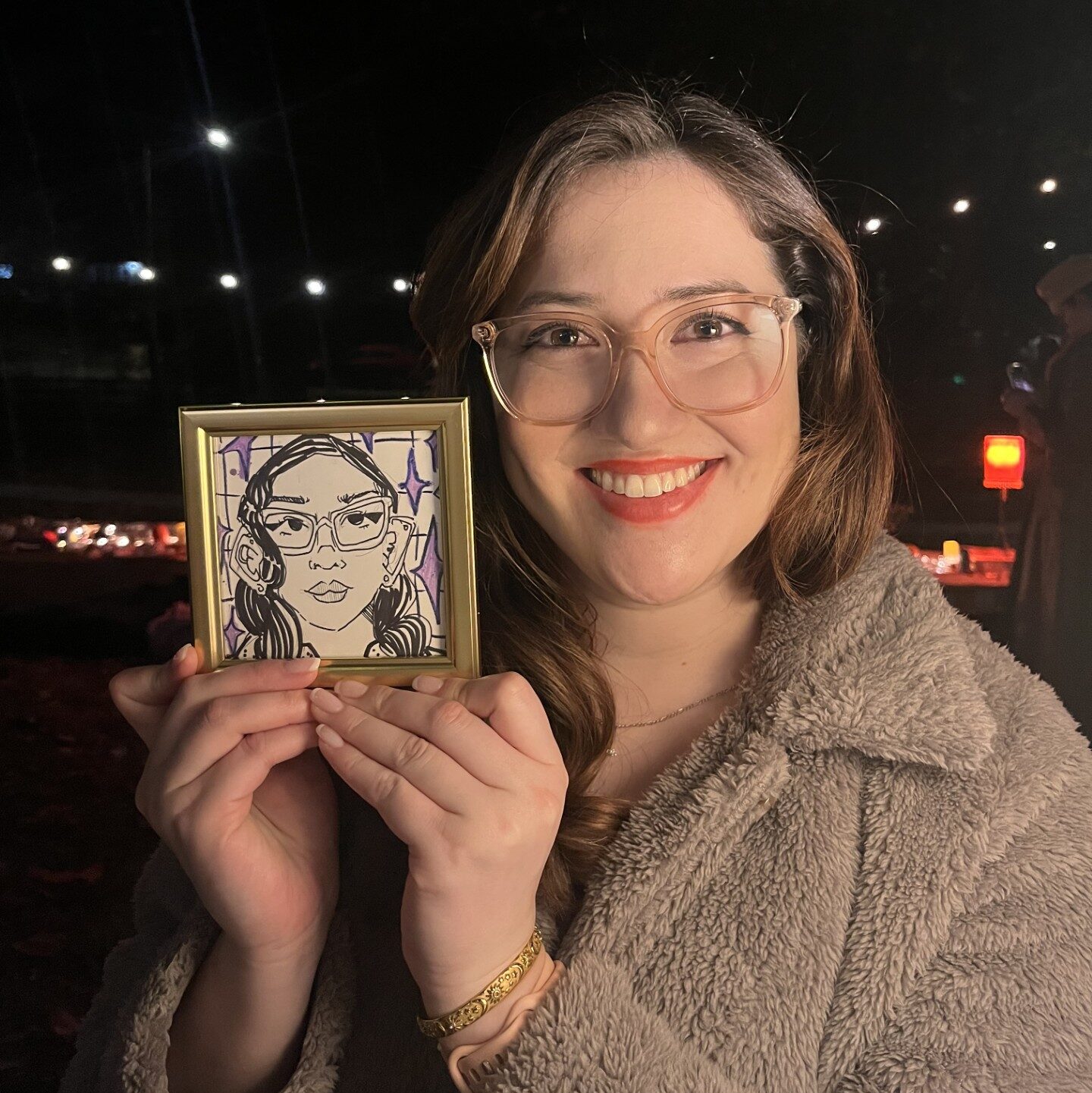 A woman holds up a small self-portrait. 