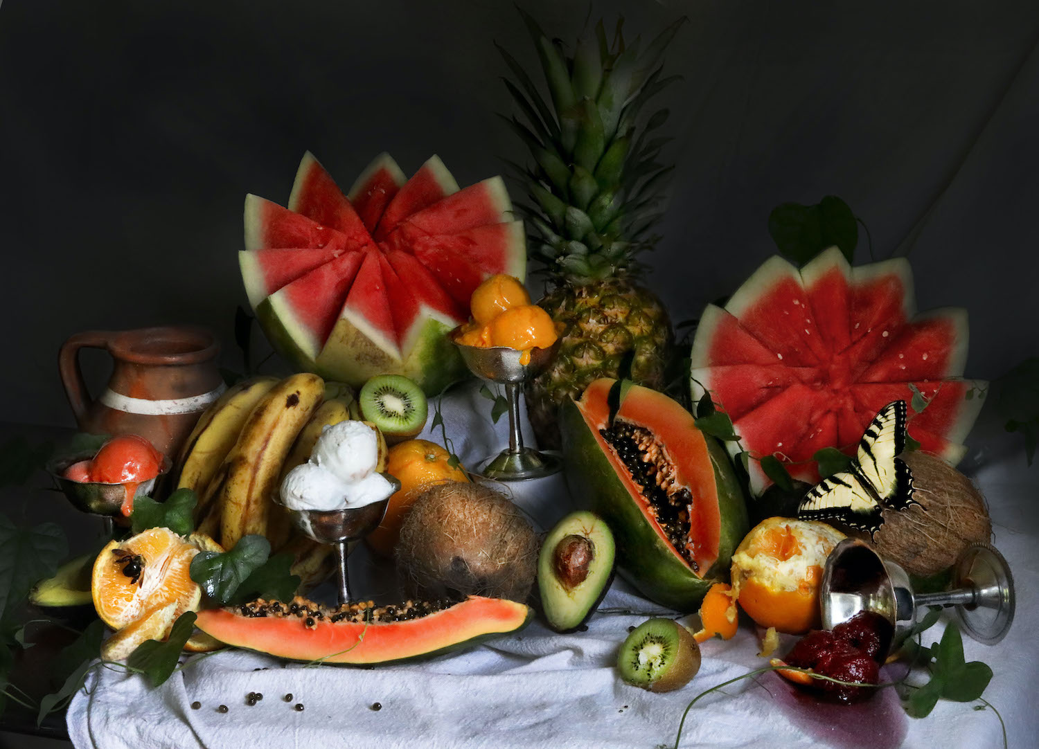 Table display of an assortment of colorful foods including watermelon, avocado, papaya, kiwi, ice cream and more