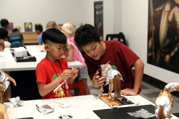 Two boys wrapping a horse in armor in ArtQuest