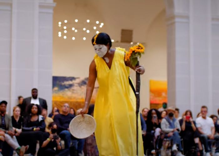 María Magdalena Campos-Pons in a yellow dress with white paint on her face