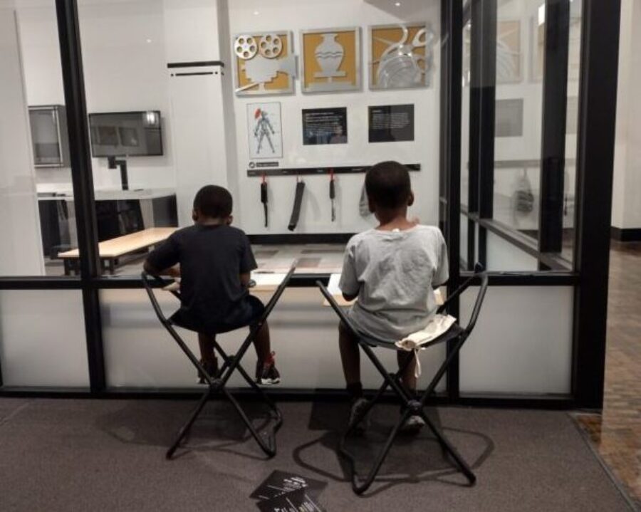 Two young boys sitting on stools drawing