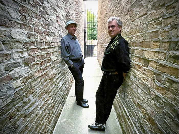 Members of The Andrews leaning up against tall rock walls in a skinny alley
